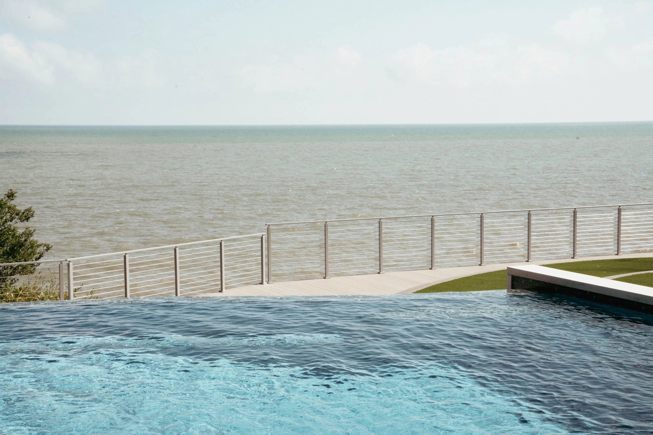 Infinity pool meeting a rod railing that separates the terrace from open water