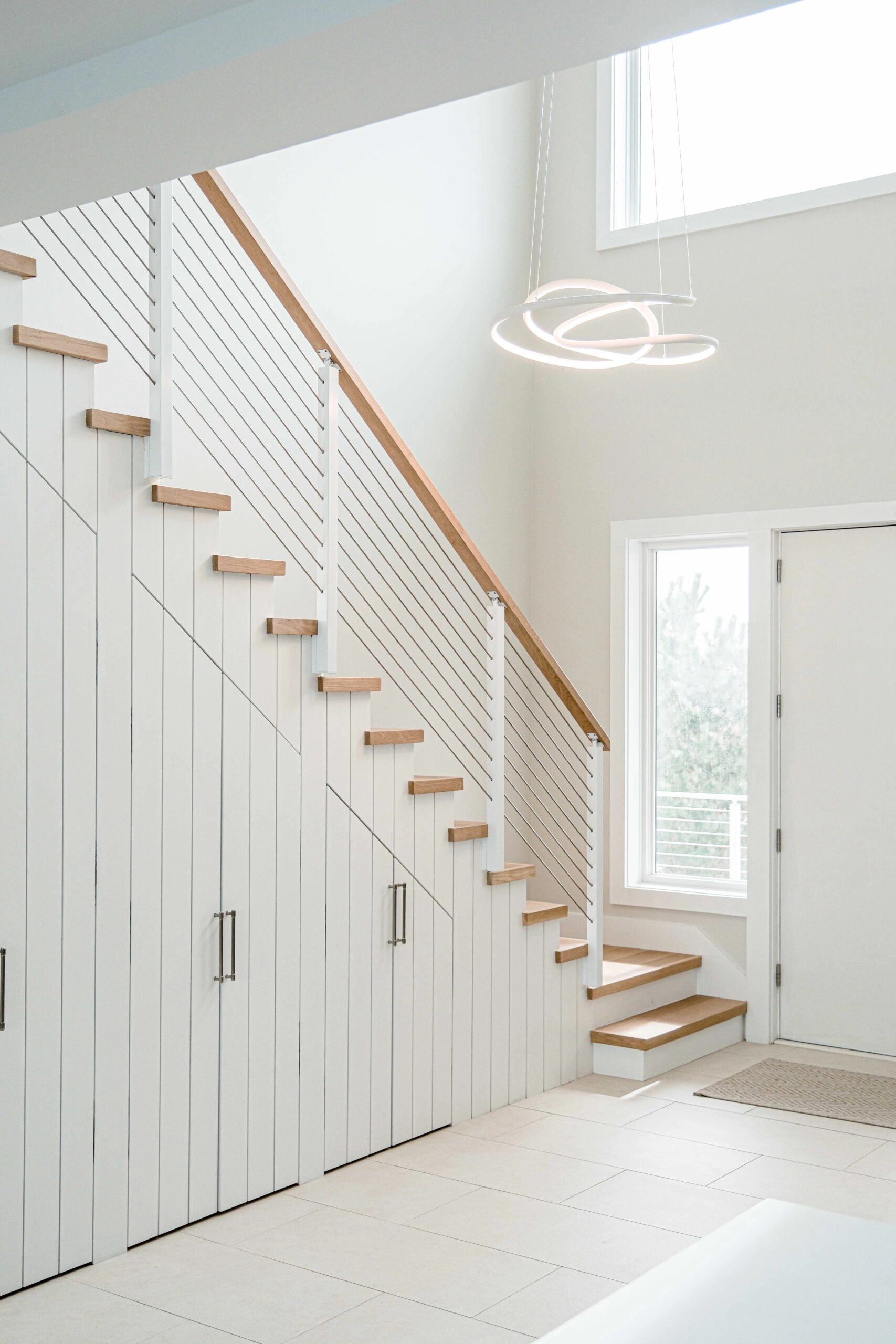 Tall entry with the stair, shiplap wall and daylight from the front door