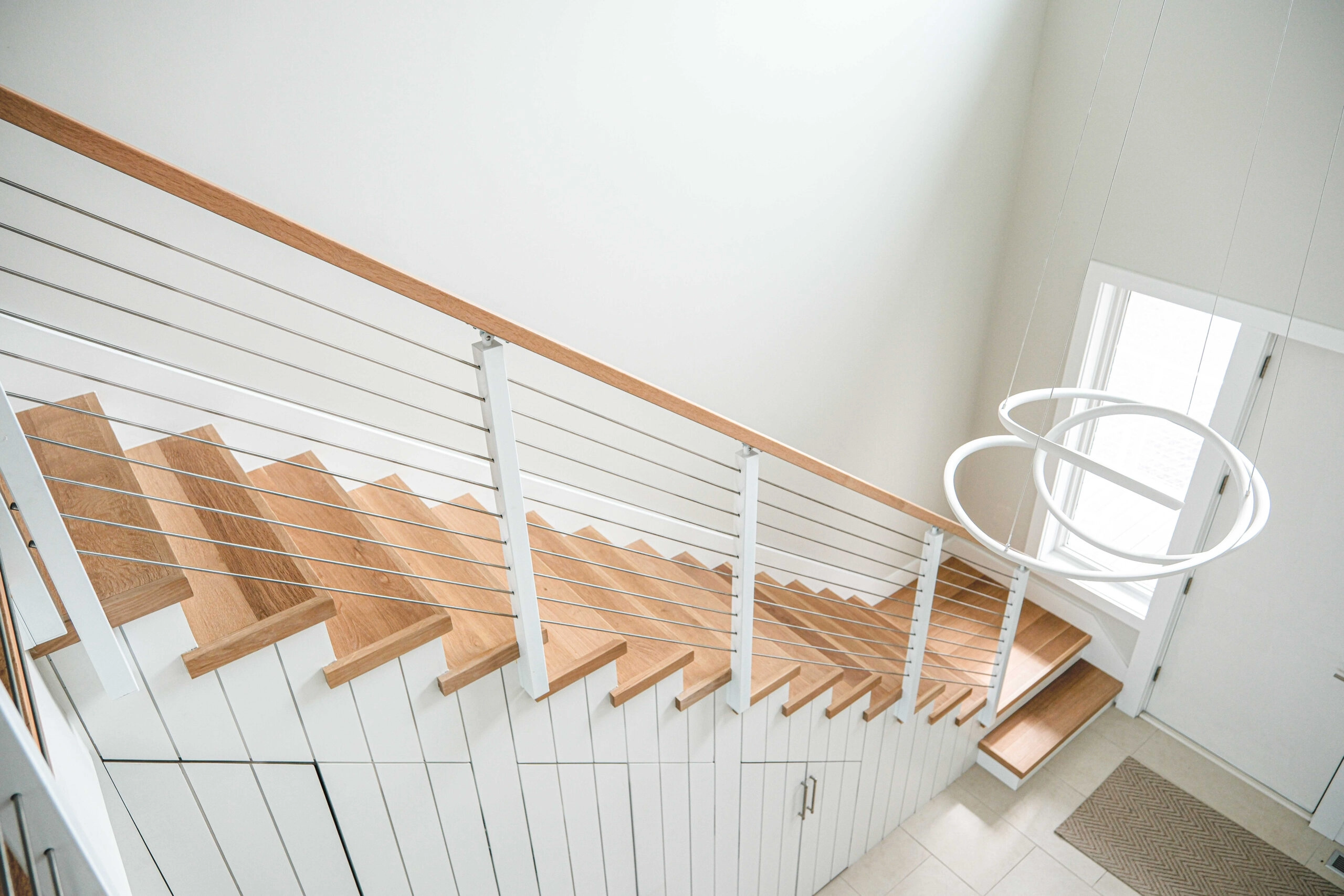Looking down the stairwell toward the front door and a ring pendant