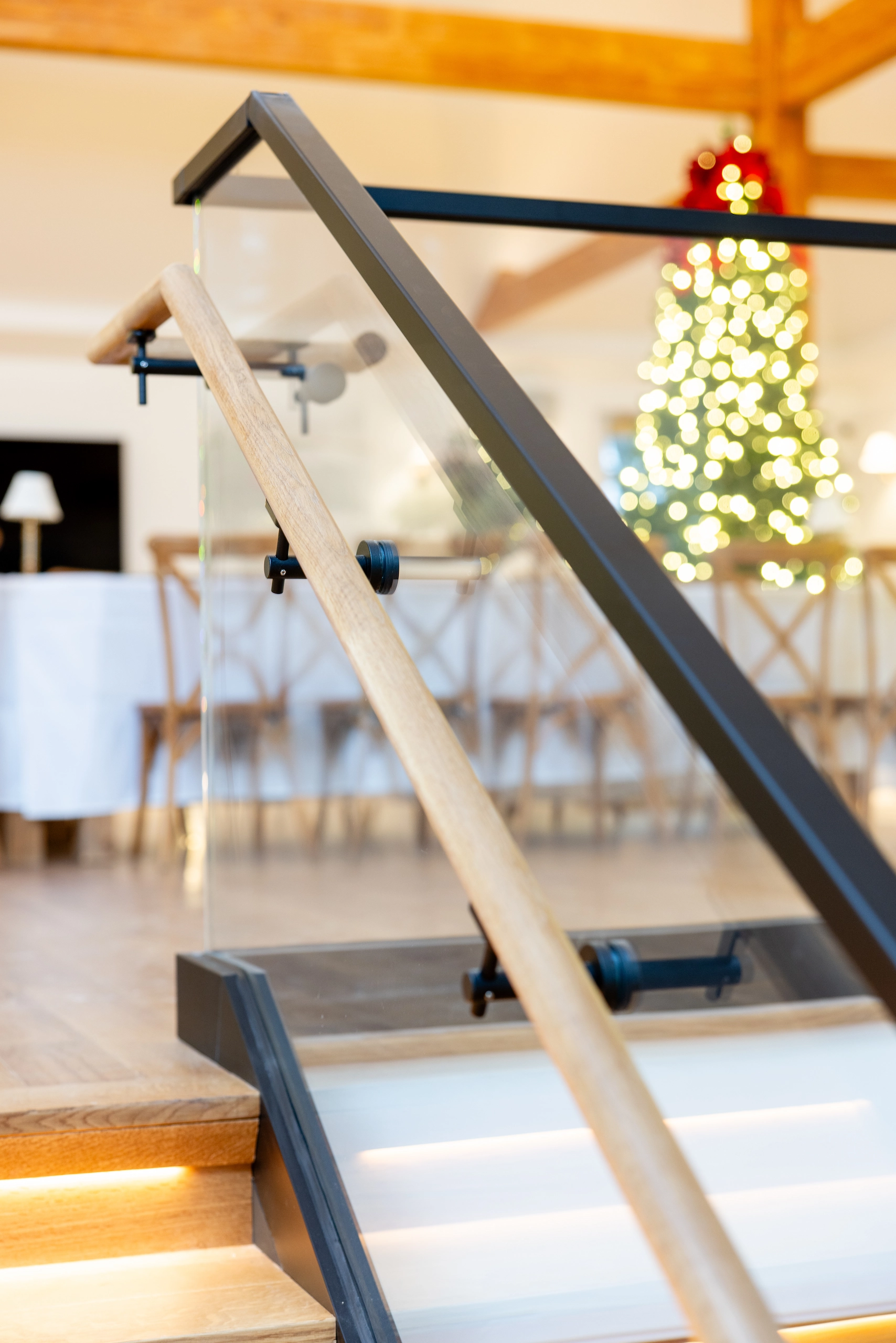 Angled glass panel and wood handrail with a dining room beyond