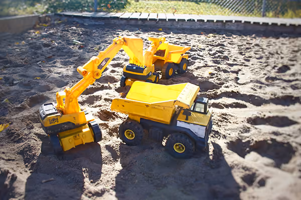 Toy trucks and toy diggers in Kreative Kids sandpit area.