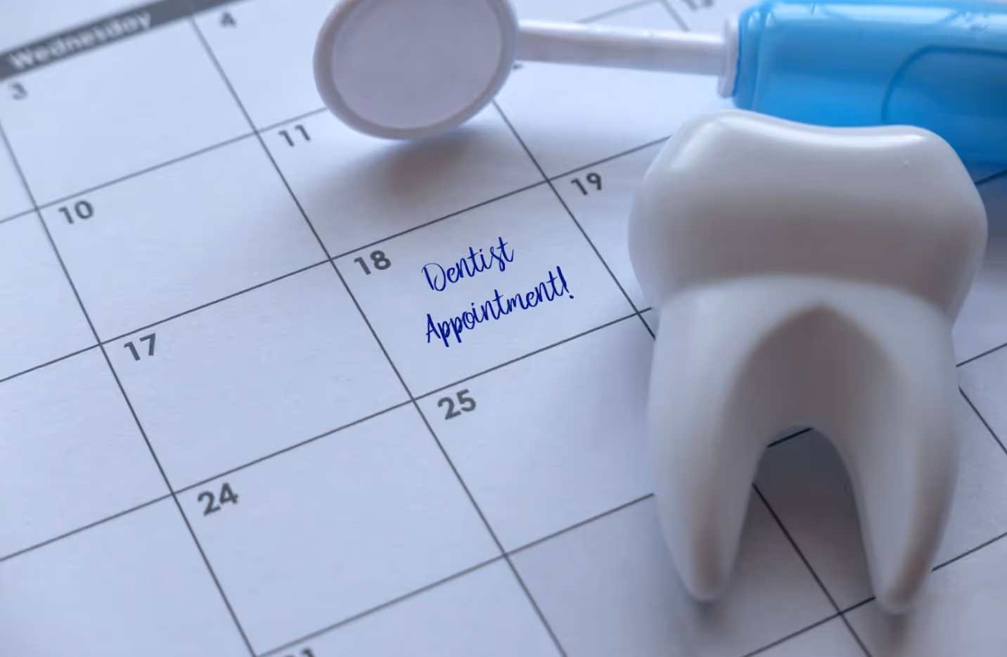 Calendar marked with “Dental Appointment” next to dental tools and a tooth model