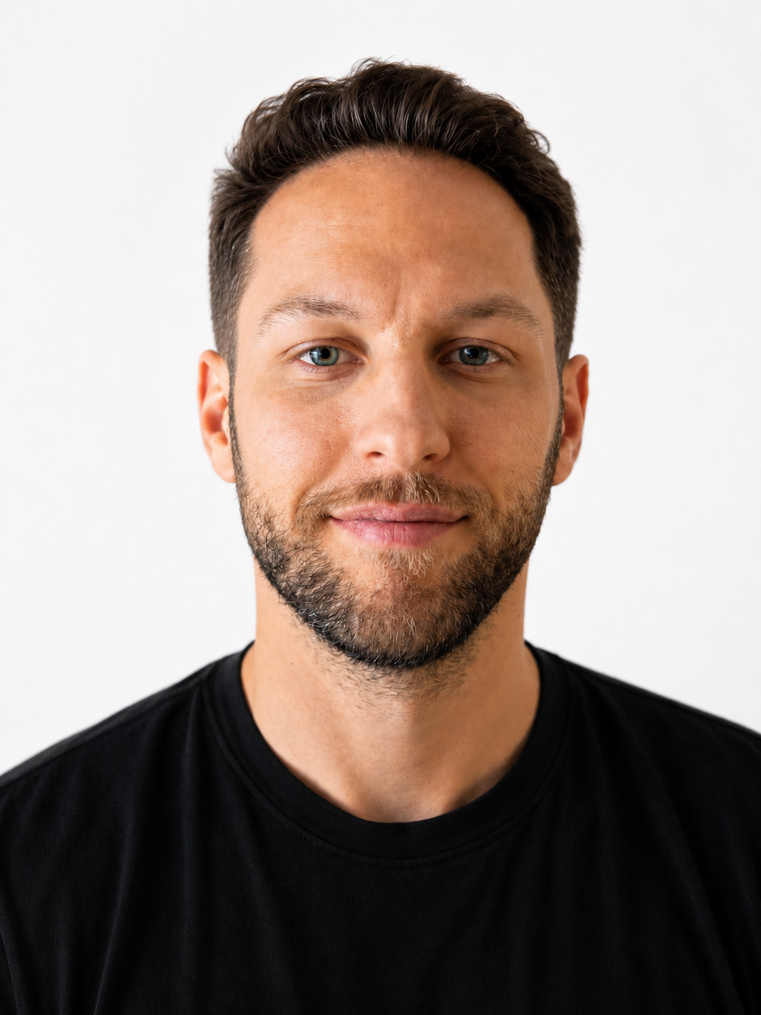 Close-up of a man with short dark hair, light beard, blue eyes, wearing a black shirt, smiling slightly.