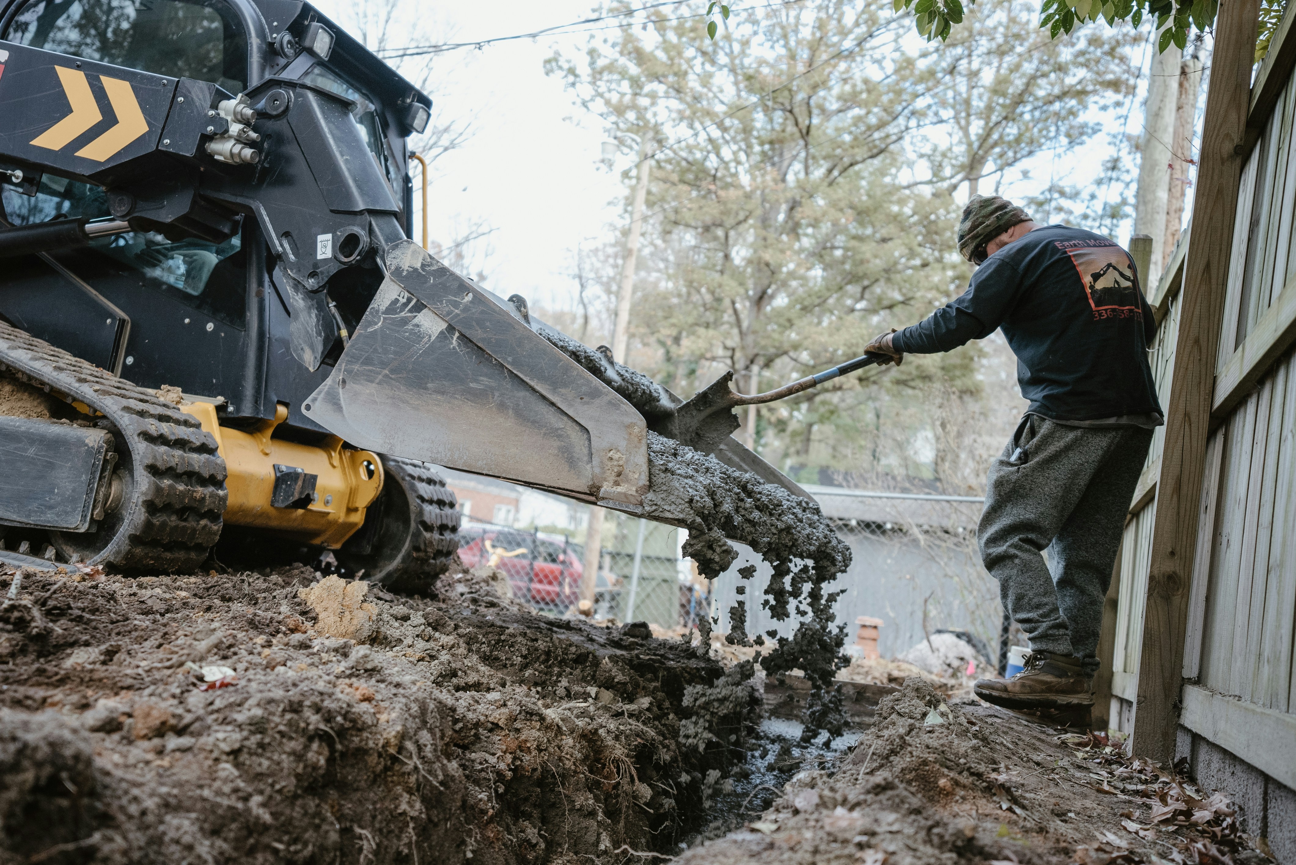 Worker and heavy machinery digging