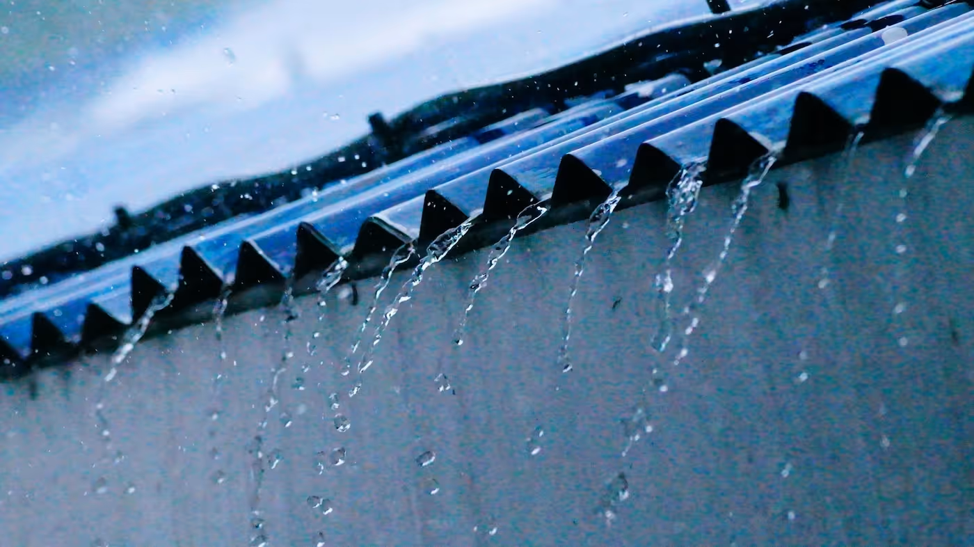 Water dripping off triangular roof edge pieces on a rainy, overcast day.
