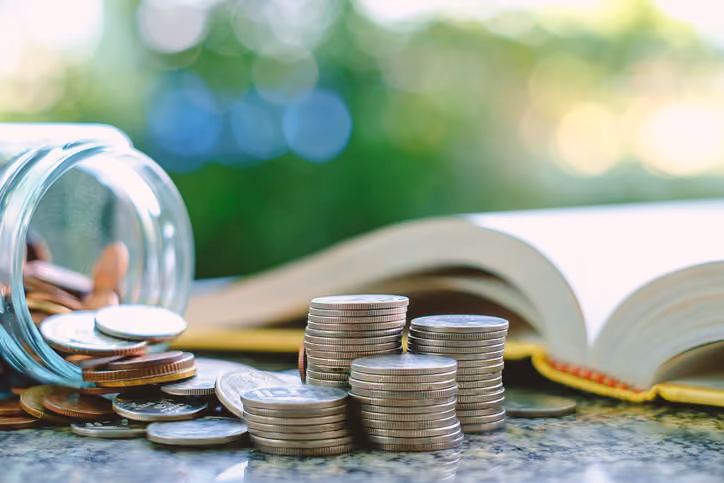 A pile of coins next to a book. Equity in a foreclosure.