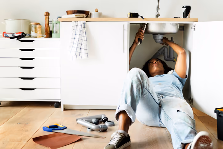 A woman fixing her sink and trying to sell her home that needs repairs.