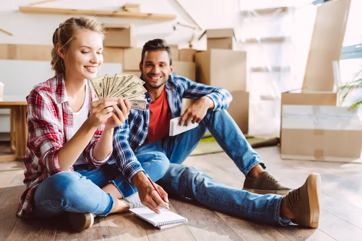 A young couple holding cash from a we buy houses company.