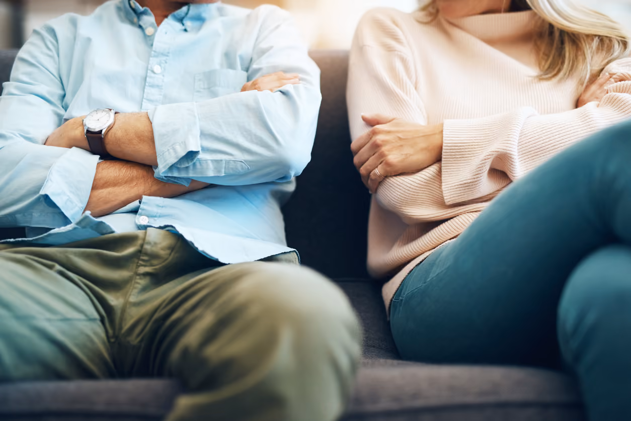 A couple sitting by each other on a couch trying to figure out what will happen to their mortgage after divorce.