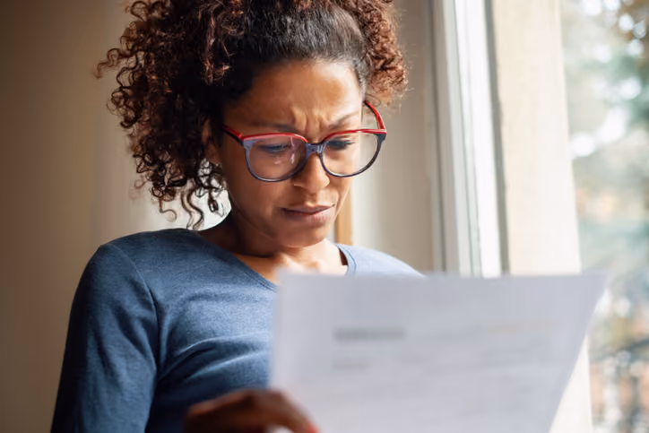 A woman reading a foreclosure notice wondering if foreclosure will ruin her credit.