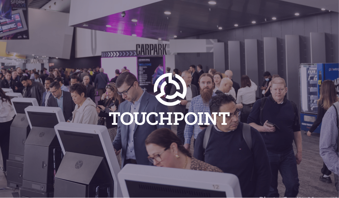 Touchpoint logo over delegates using self check-in kiosks in a busy convention foyer