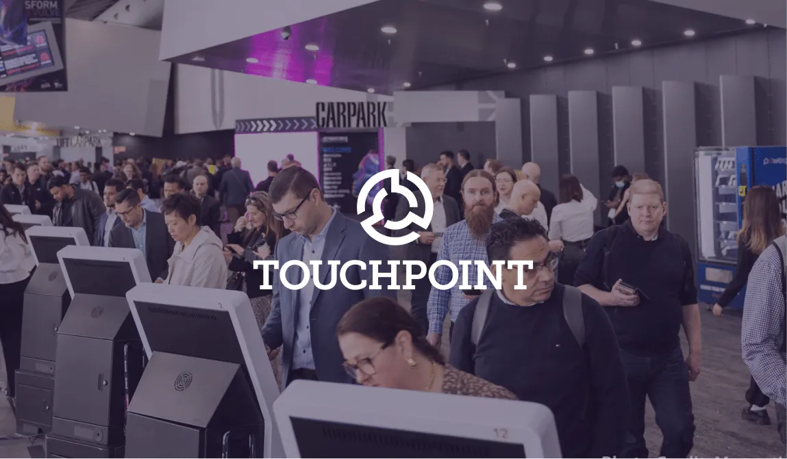 Touchpoint logo over delegates using self check-in kiosks in a busy convention foyer