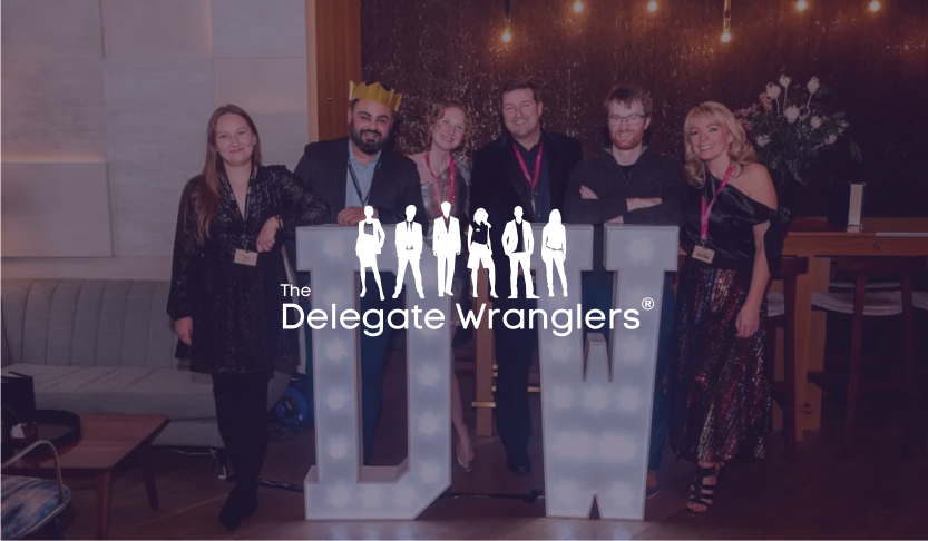 The Delegate Wranglers logo over six guests posing with giant lit DW letters at a party