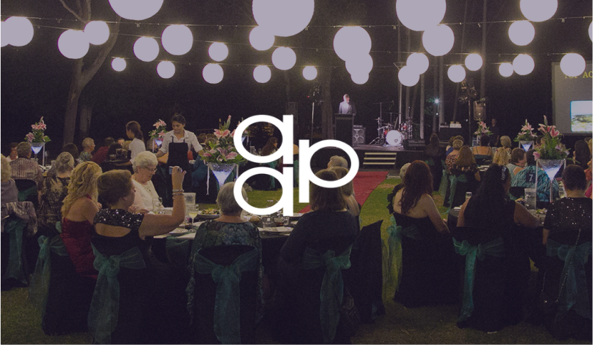AA&P logo over guests at an outdoor evening gala dinner under hanging lanterns