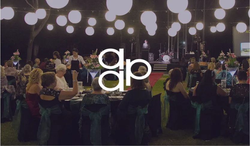 AA&P logo over guests at an outdoor evening gala dinner under hanging lanterns