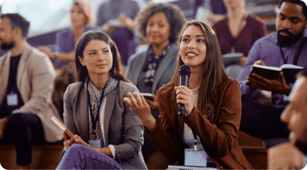 A young lady holding a microphone addressing an audience