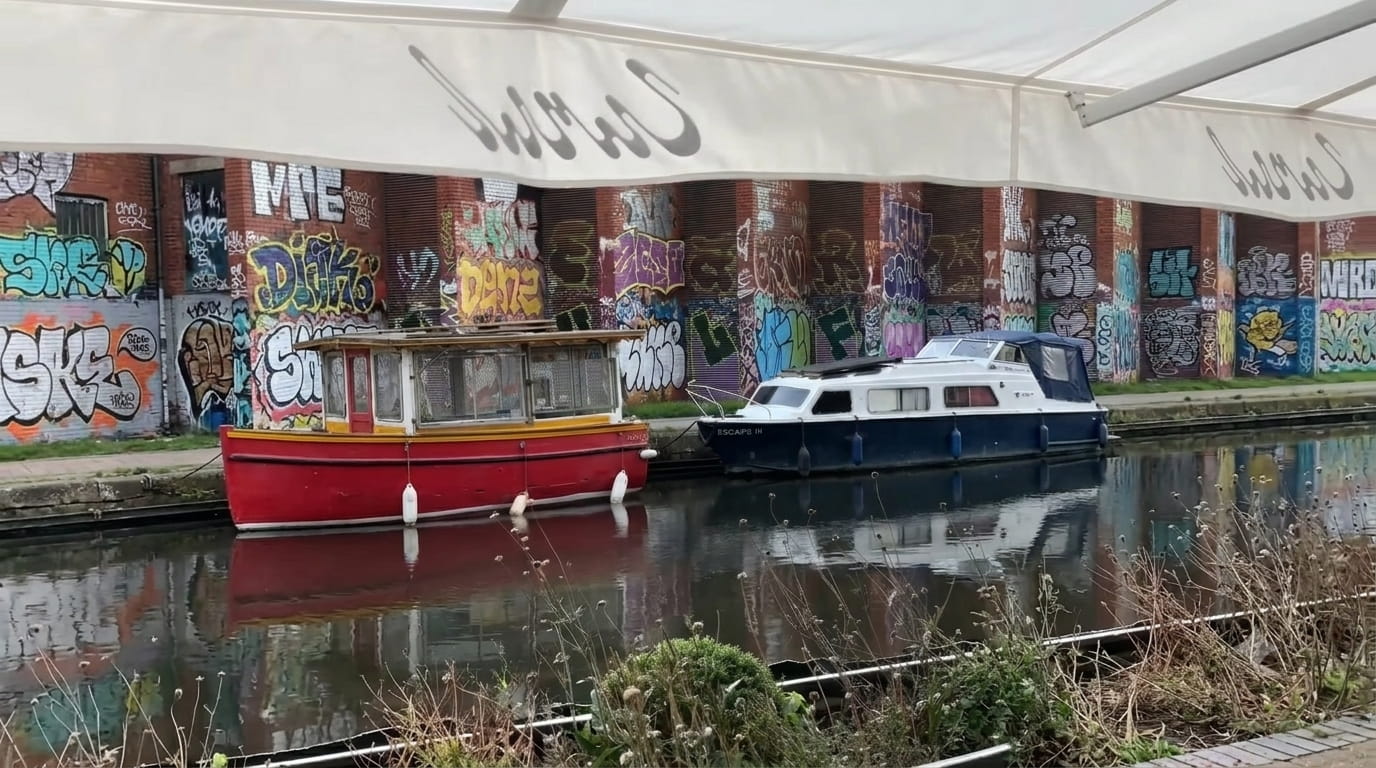 Narrowboat passing Canal Restaurant's south-facing terrace in Westbourne Park