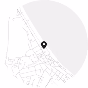 Vereinfachte graue Straßenkarte mit einem schwarzen Standortmarker nahe der Küstenlinie am rechten Rand.