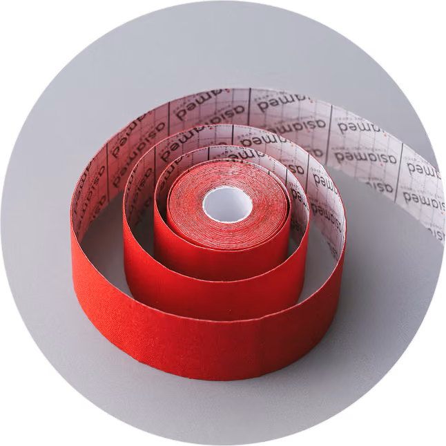 Aufgerolltes rotes Kinesiologie-Tape mit einer Klebefläche, die das Wort "osiamed" mehrfach trägt, auf grauem Hintergrund.