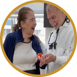 Smiling dentist showing an elderly woman a dental model during a consultation.