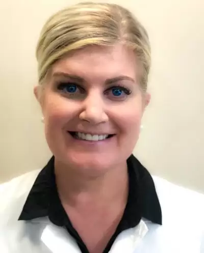 Smiling woman with blonde hair in a white coat and black collared shirt.