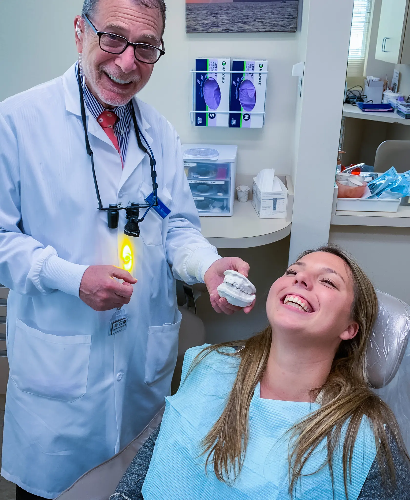 A dentist in Stamford, CT, shows a patient her before-and-after smile model during a completed smile transformation reveal.