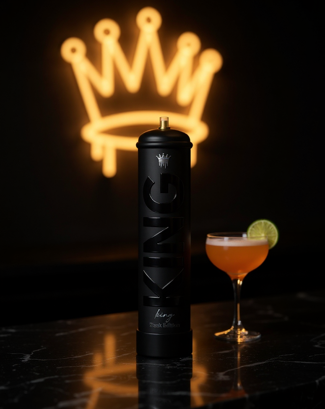 Matte black can labeled 'KING King Black Edition' standing on a reflective black marble surface with a cocktail glass with orange drink and a lime wheel garnish beside it, illuminated by a blurred glowing crown symbol in the background.