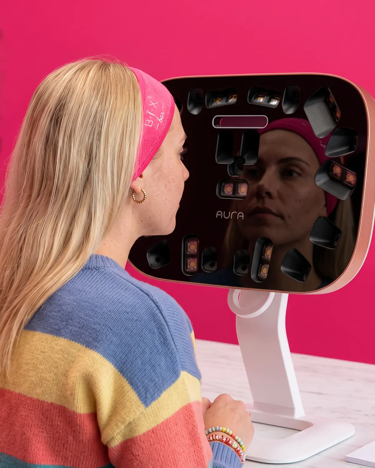 Aura 3D Face Scan: una donna con fascia rosa si guarda nel dispositivo Aura che analizza il suo viso