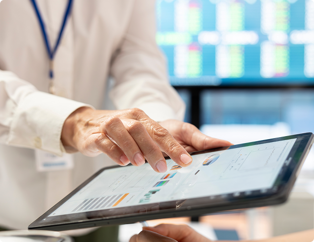 Close-up of hands interacting with a tablet displaying charts and data in an office setting.