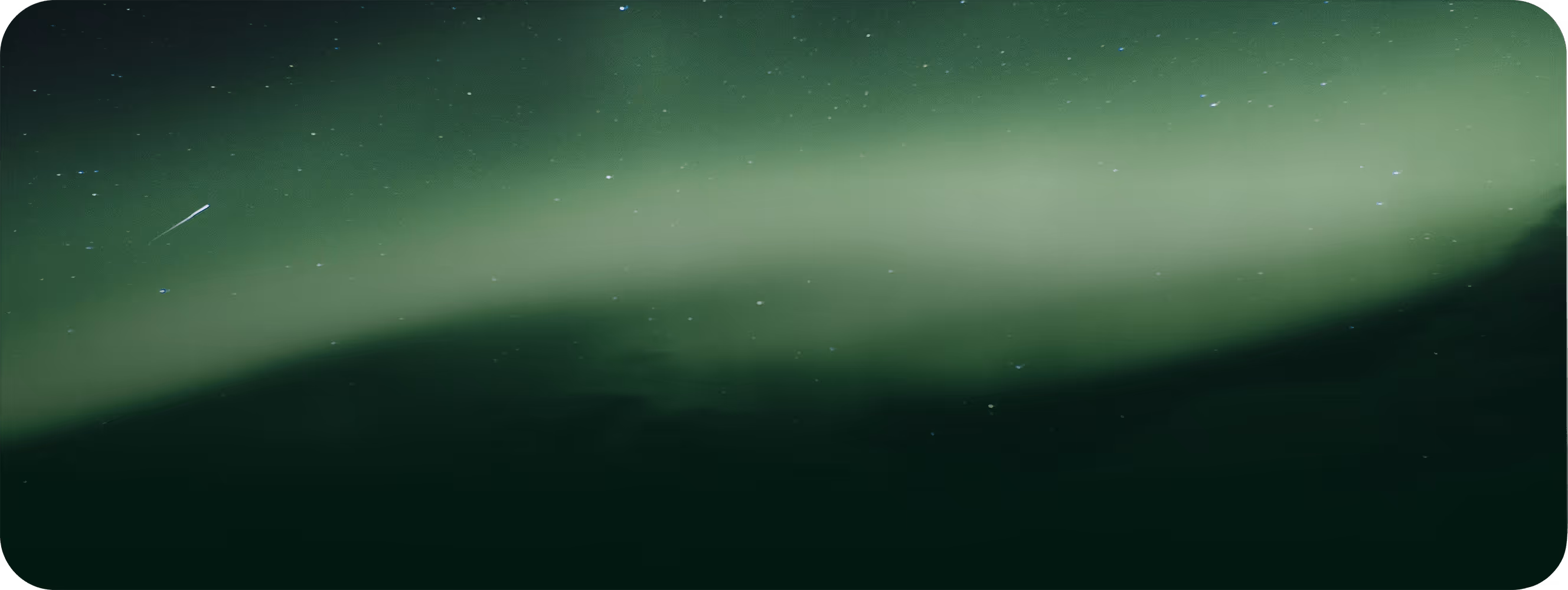 Green aurora borealis lights up the night sky filled with stars and a faint shooting star.