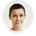 Portrait of a woman with short dark hair and a light pink shirt, smiling gently at the camera.