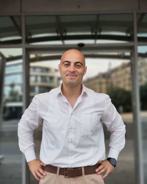 Manager de proximité en chemise blanche devant un immeuble parisien