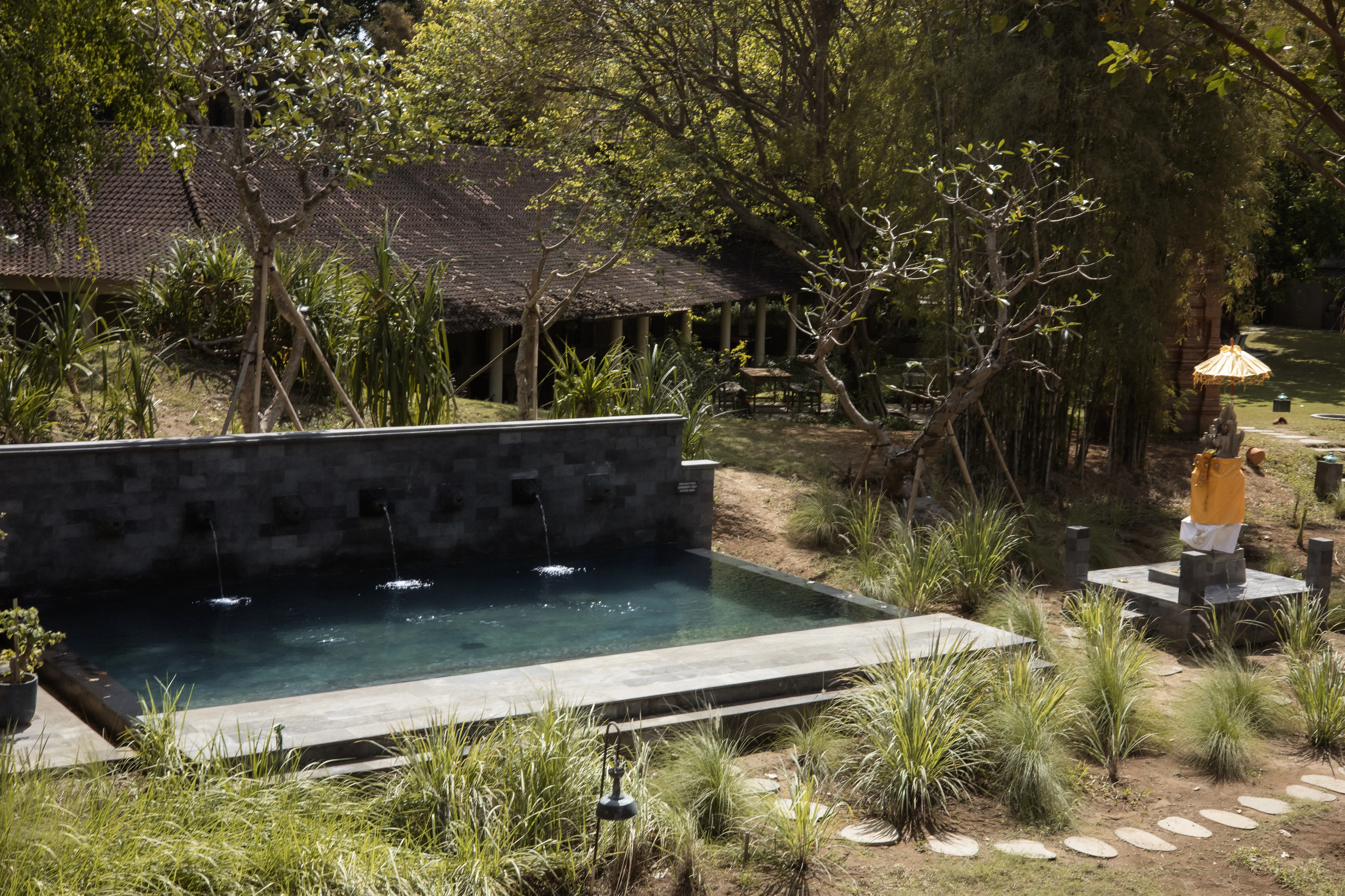 Outdoor stone purification pool with water fountains alongside a traditional Balinese.