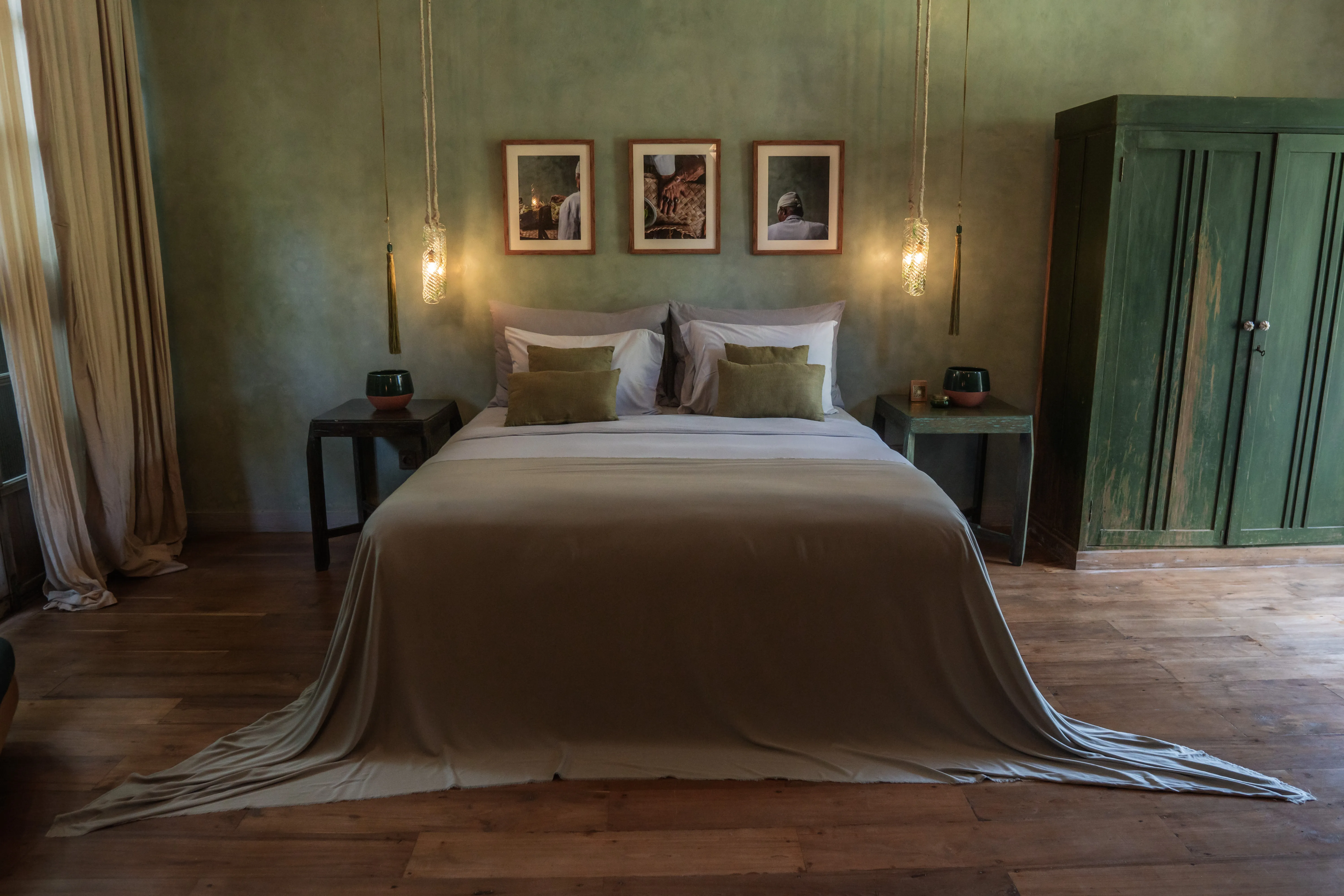 Minimalist luxury bedroom suite at The Shaba Shala featuring sage green walls, hanging pendant lights, and a dark green wooden wardrobe.