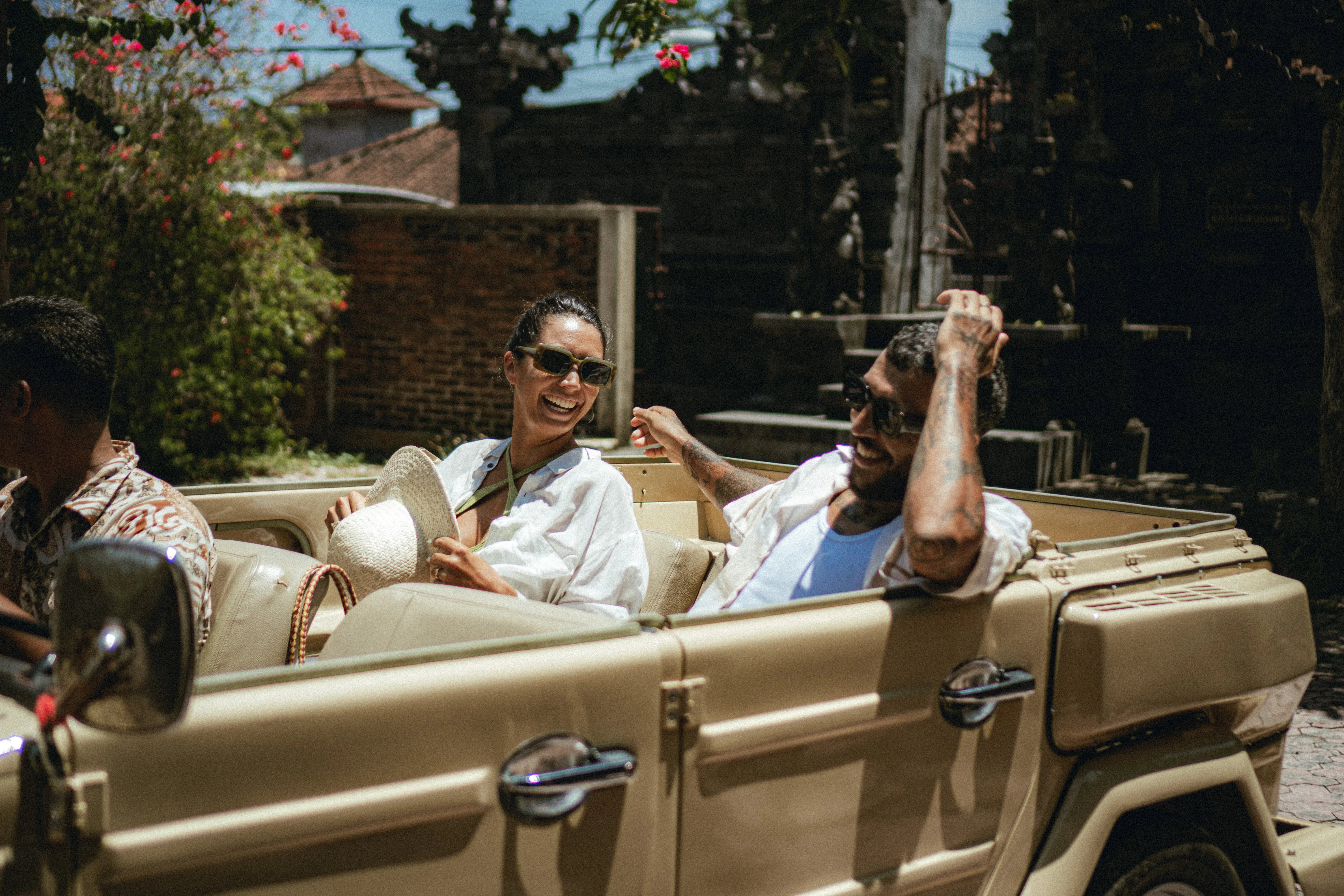 Happy couple enjoying a ride in a vintage open-top beige safari car on a Sunny day in Bali with The Shaba Shala.