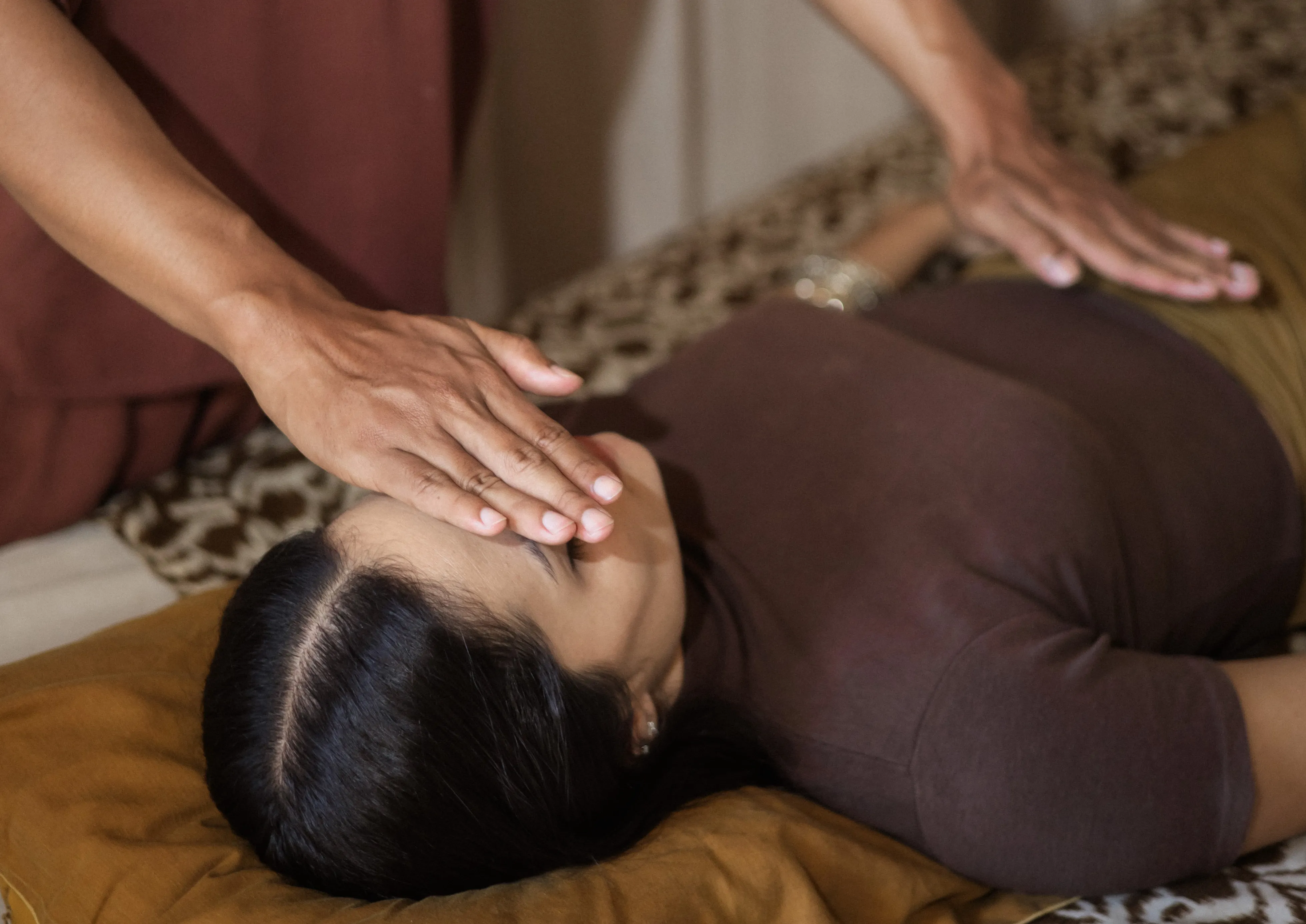 Hands gently over a guest's face and lower abdomen during an energy healing session at The Shaba Shala.