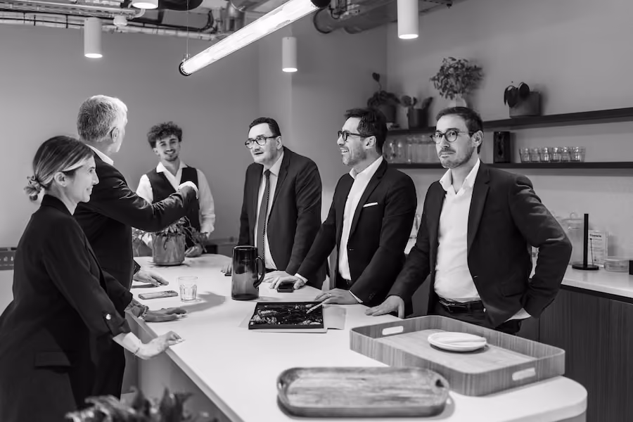 Un groupe de professionnels en réunion autour d'une table avec plans, ordinateurs portables et documents.