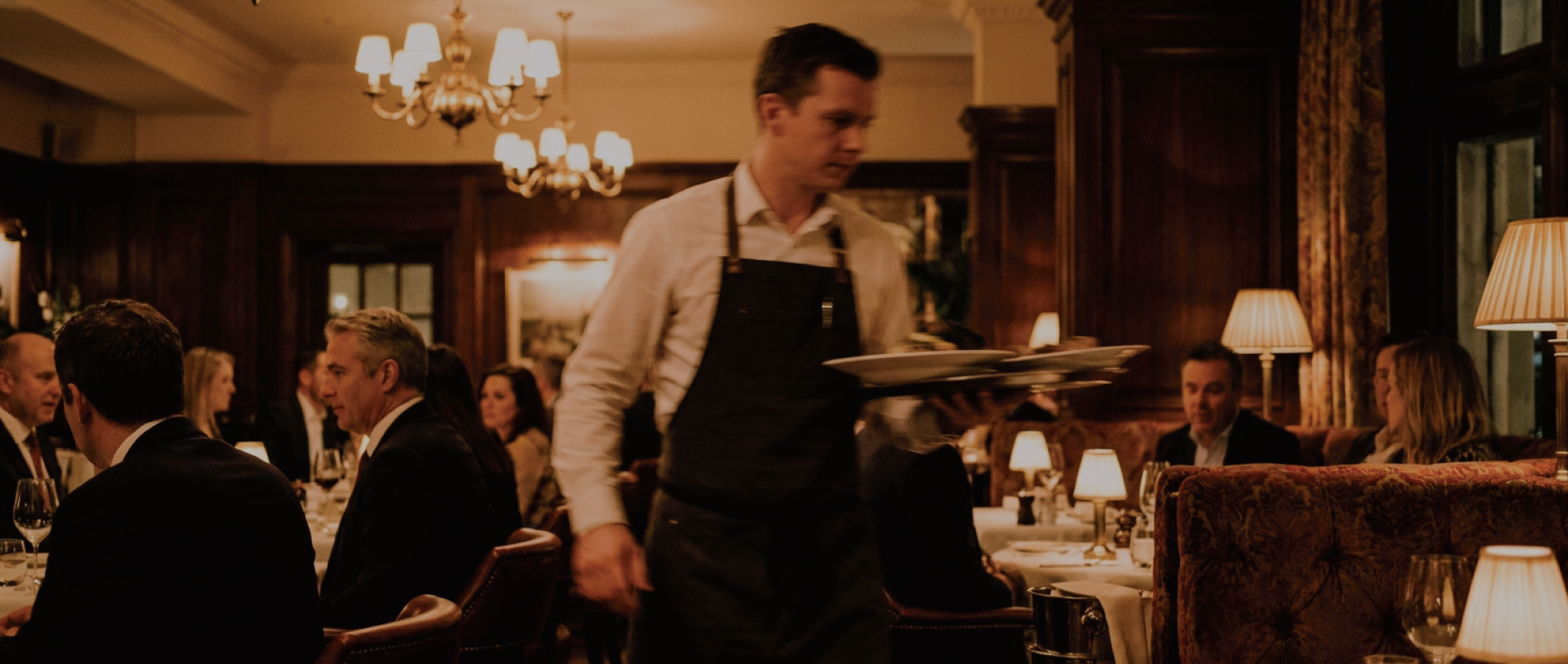 A team of servers in aprons reviewing orders and a phone before service