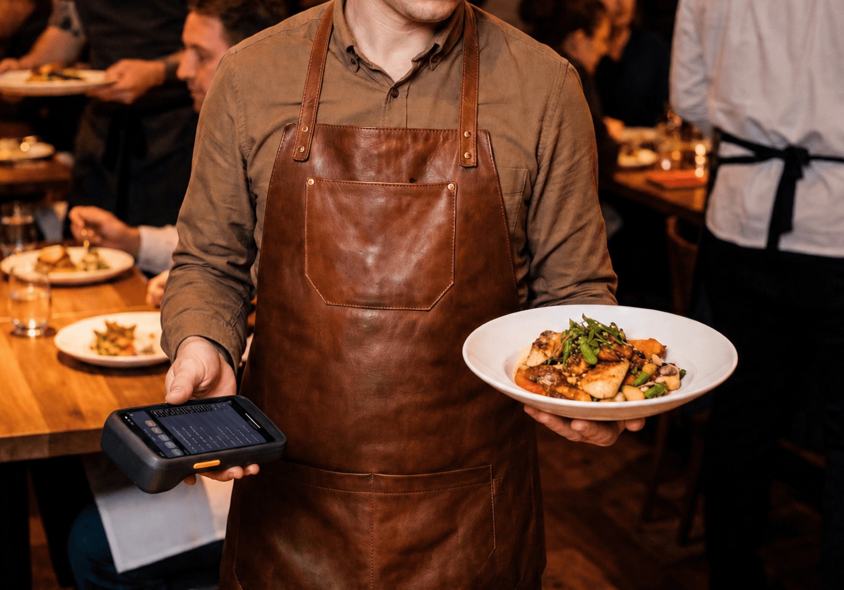 A server carrying a plate while holding an Upserve handheld for tableside orders and payments