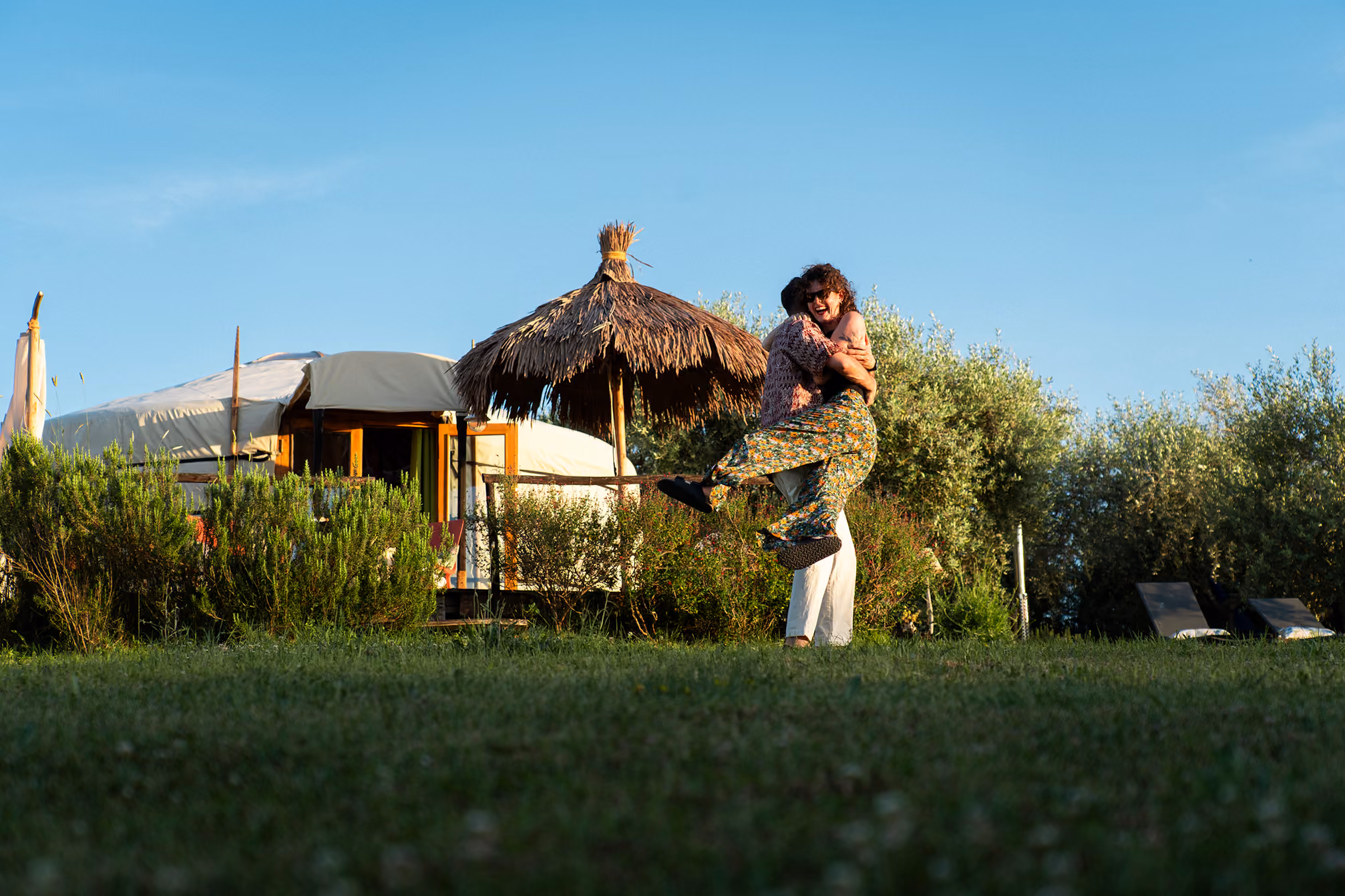 Una coppia si abbraccia nel giardino di una yurta al Glamping per coppie Due cuori e una Yurta