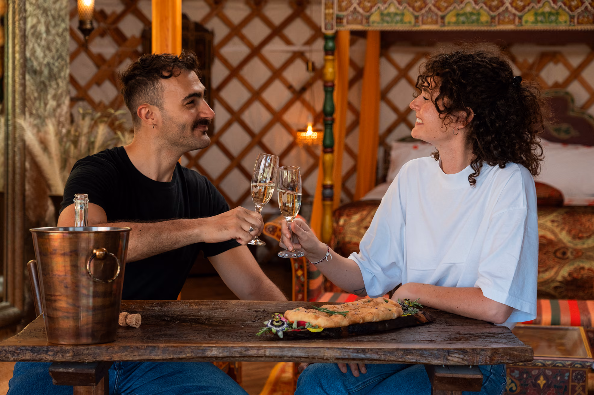 Una coppia stappa un prosecco, parte del proprio benvenuto romantico all'arrivo nella yurta al Glamping per coppie Due cuori e una Yurta