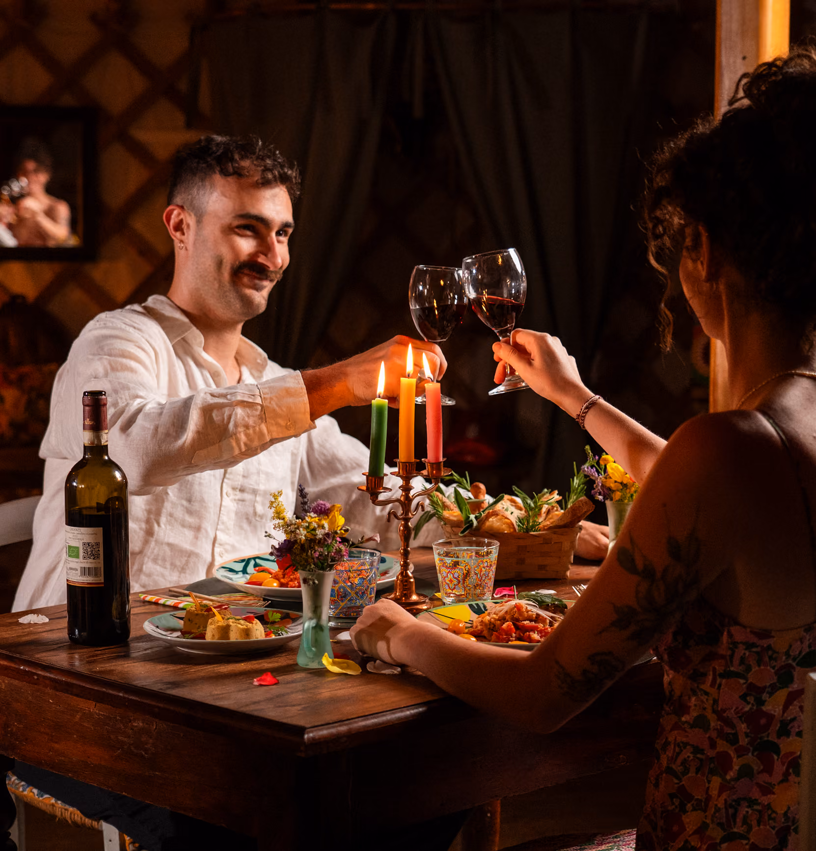 Una coppia brinda con del vino organico, parte della cena romantica, esperienza nella yurta al Glamping per coppie Due cuori e una Yurta