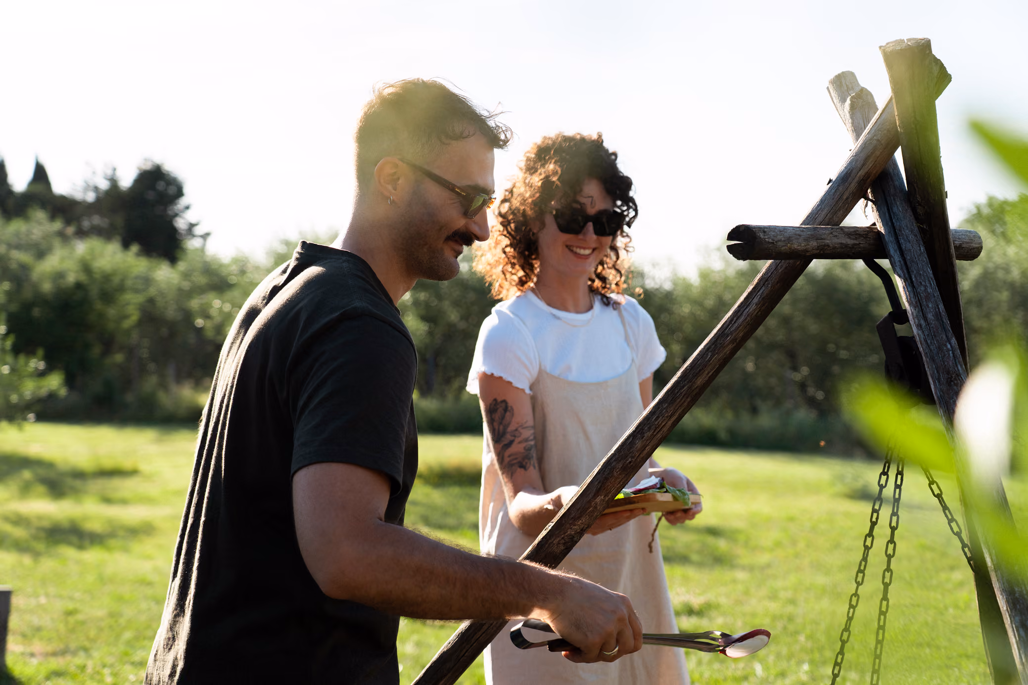 Una coppia sorridente griglia (barbecue, bbq, falò) al Glamping per coppie Due cuori e una Yurta