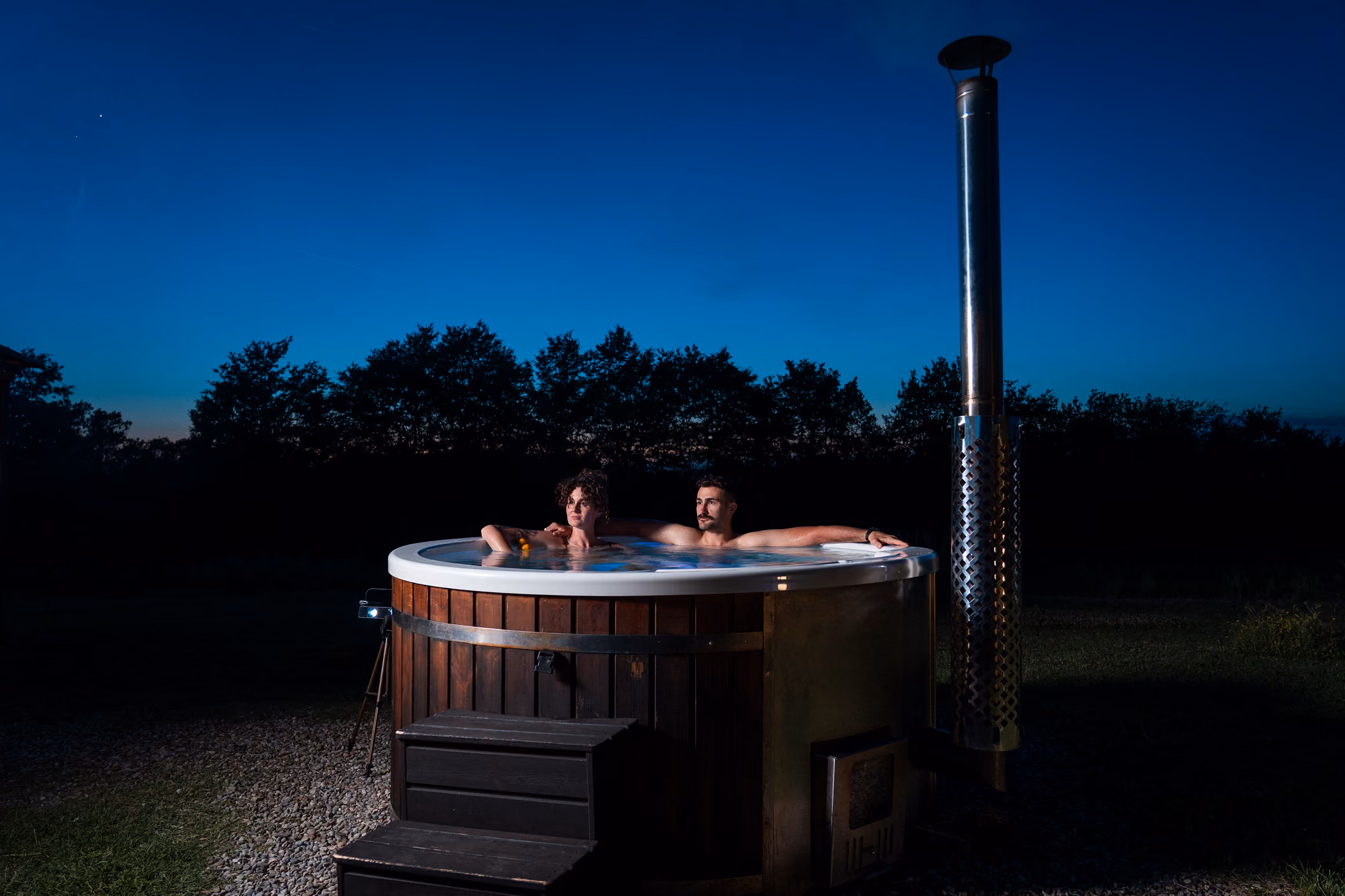 Una coppia dentro a un'hot tub (o jacuzzi o bagno caldo) fiori dalla propria yurta al Glamping per coppie Due cuori e una Yurta