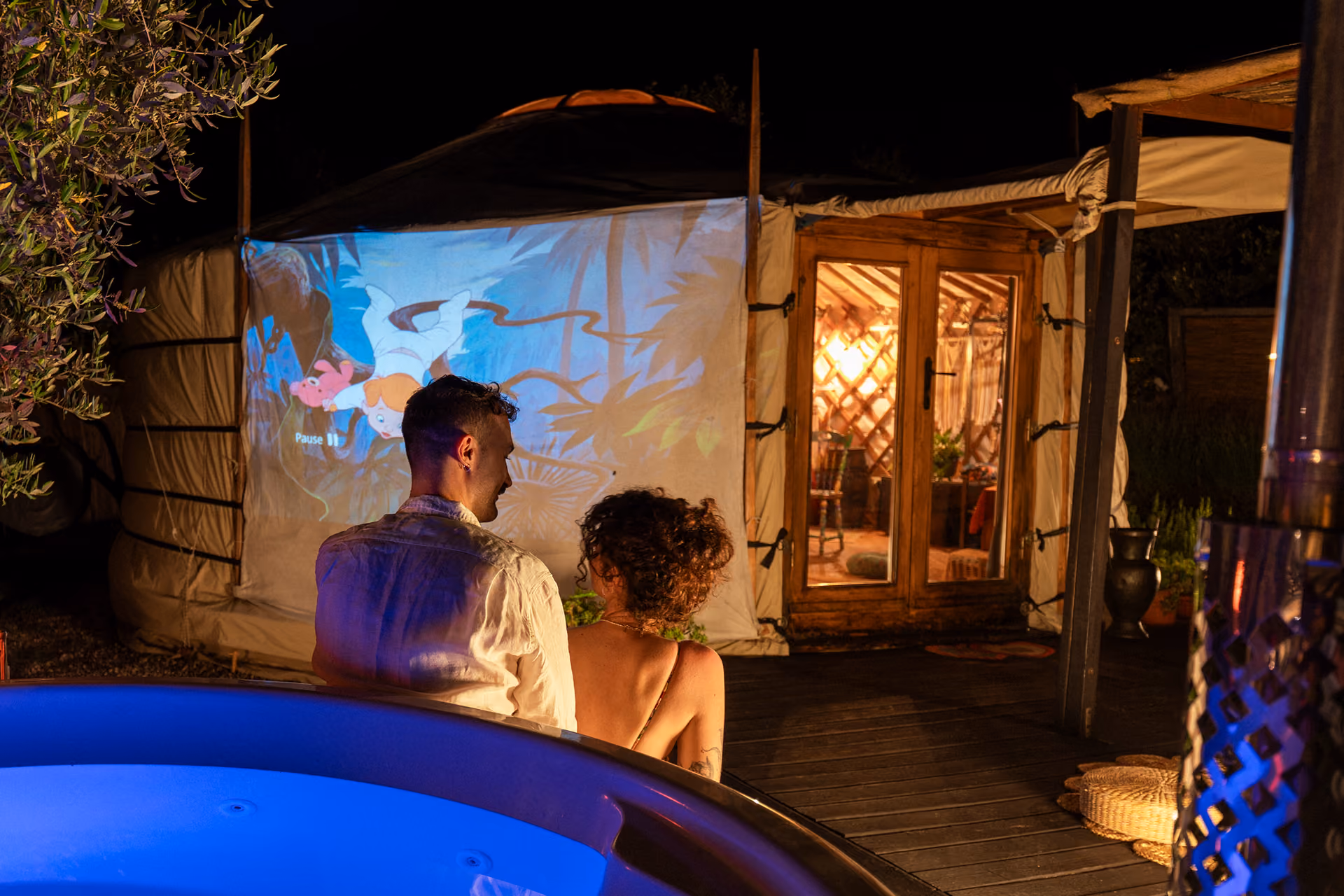 Una coppia guarda un film al cinema privato fuori dalla propria yurta al Glamping per coppie Due cuori e una Yurta