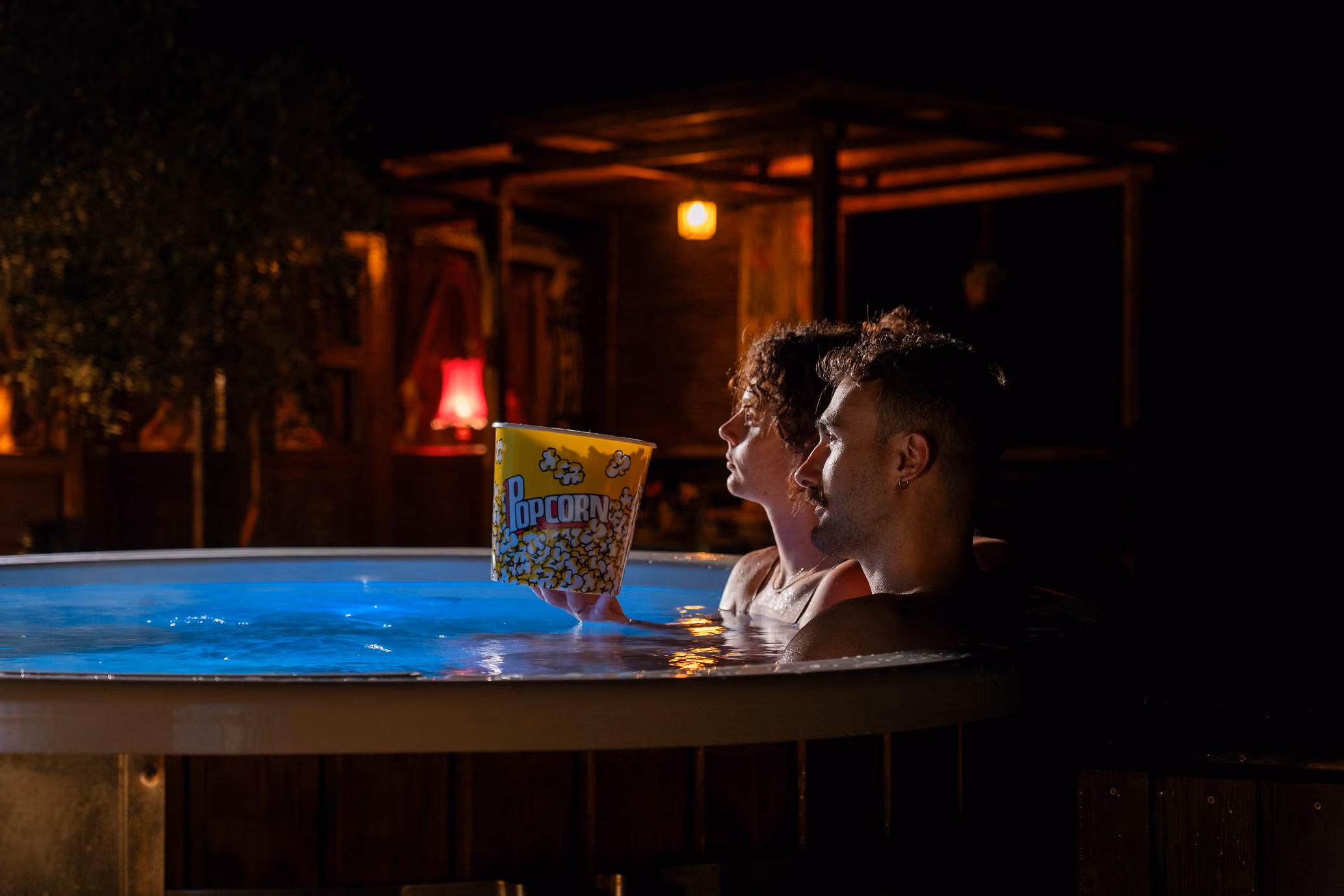 Una coppia condivide popcorn mentre guarda un film nel cinema privato fuori dalla yurta al Glamping per coppie Due cuori e una Yurta (immersi in una hot tub / jacuzzi / bagno caldo)