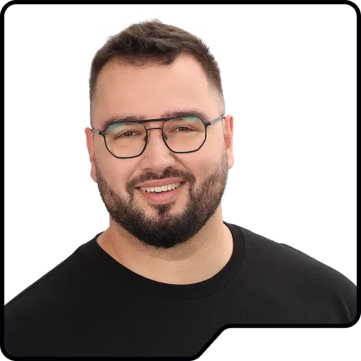 Yossi, a bearded team member wearing glasses, smiling in a black t-shirt.