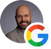 Smiling bald man with beard in a brown jacket, Google logo overlay on bottom right.