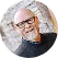 Smiling older man with glasses and a trimmed beard wearing a dark gray shirt.
