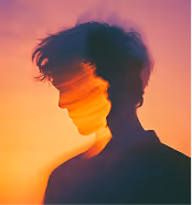 Silhouette of a person with a double exposure effect against a warm orange and purple background.